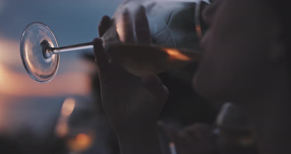 Close up of attractive woman drinking wine at sunset