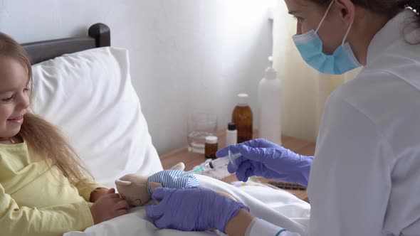 Young Cute Caucasian Slavic Woman Nurse or Doctor Pediatrician Gives Injection to Teddy Bear