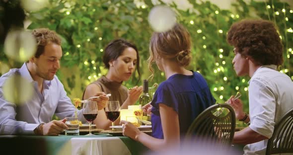 Four People, Two Couples Happy Talking and Eating During a Romantic Gourmet Dinner or Lunch