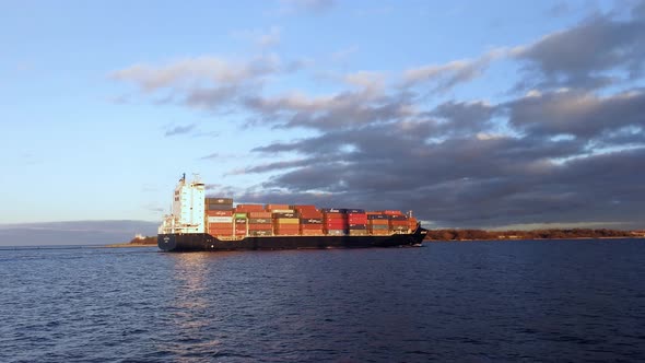 Ship slowly comming into the port and passing by. Sunny autumn day.