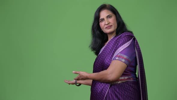 Mature Happy Beautiful Indian Woman Showing Something To the Back Wearing Sari Traditional Clothes