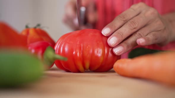 Closeup Cutting Red Ripe Tomato with Knife on Cutting Board in Slow Motion
