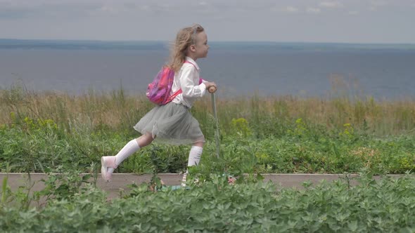 Beautiful Child Preschooler Riding Scooter in front of River on Nature Place for Advertising