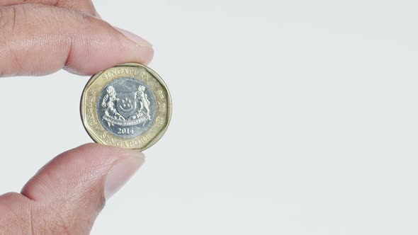 Fingers Hold A Singapore Dollar Coin Back