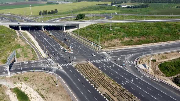 aerial forward drone shot of a multiple directions highway junction, surrounded by grass end trees.