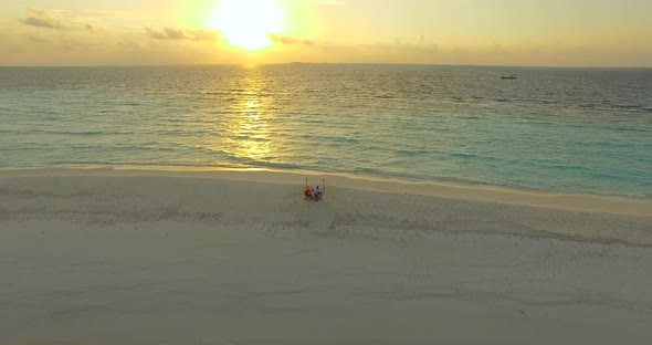 Aerial drone view of a man and woman eating dinner and dining on a tropical island beach