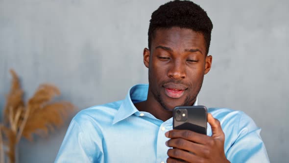 Young african american guy talking on video call with friend using phone and internet