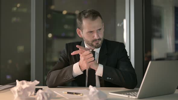 Upset Businessman Looks Stressed on Office Desk at Night