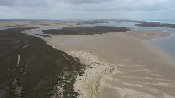 Aerial footage of a white sandy beach at the mouth of the River Murray in regional Australia