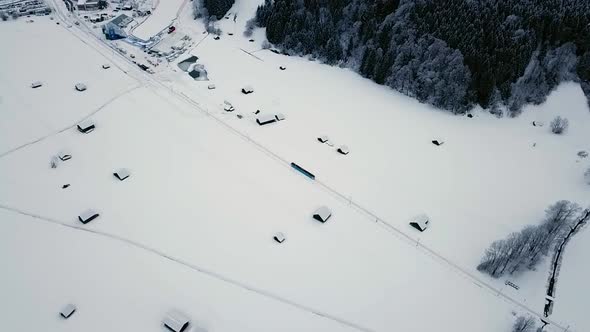 Aerial following a train going through Grainau town in a snowy winter. Bavaria, Germany.