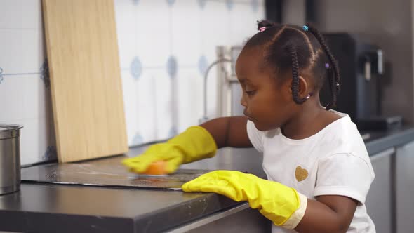 Little Afroamerican Girl Cleaning in Kitchen at Home