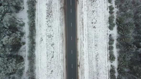 Drone movement along a snow-covered road and winter forest.