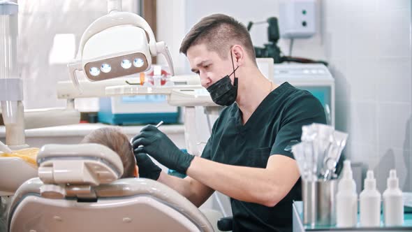 Young Dentist Checking the Mouth of a Boy - Looking Back in the Camera