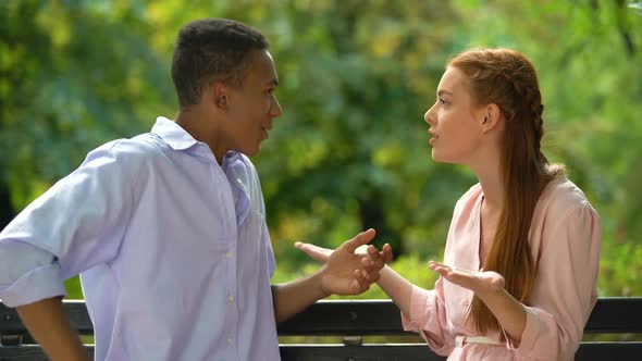 Emotional Teenagers Arguing and Quarreling Sitting on Bench in Park, Conflict