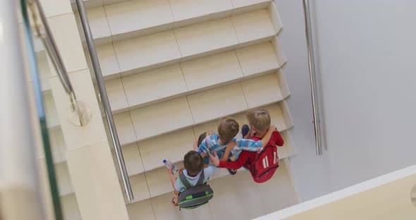 Video of top view of caucasian boys running upstairs at school