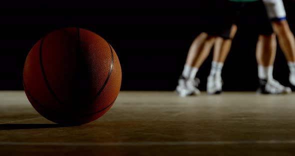 Basketball in the court while players playing basketball in the background 4k