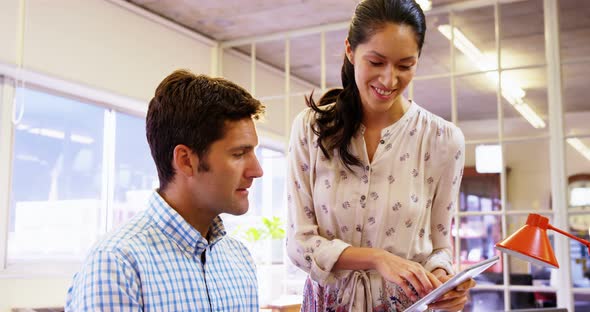 Male and female business executive interacting over digital tablet