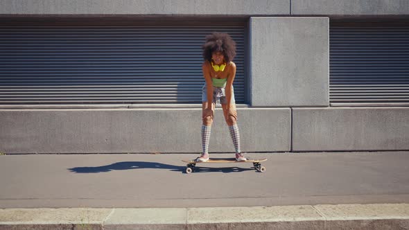 Beautiful young woman cruising around the city with her longboard.