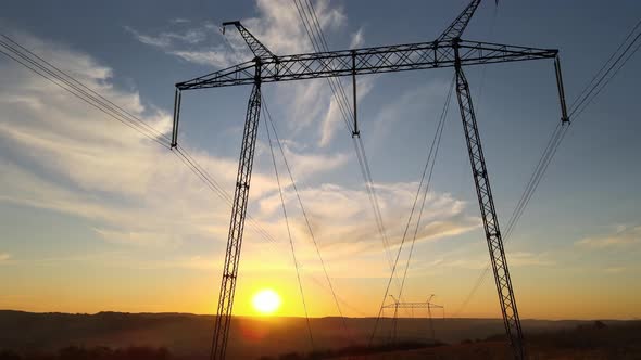 Dark Silhouette of High Voltage Tower with Electric Power Lines at Sunrise