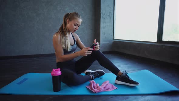 Young Business Lady Who Deals in the Gym Looks at Incoming Messages on the Phone