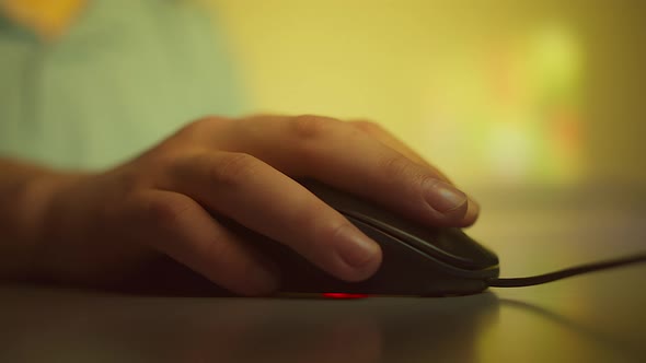 Close-up of a man hand, working on a computer, clicks the buttons of a computer mouse and turns