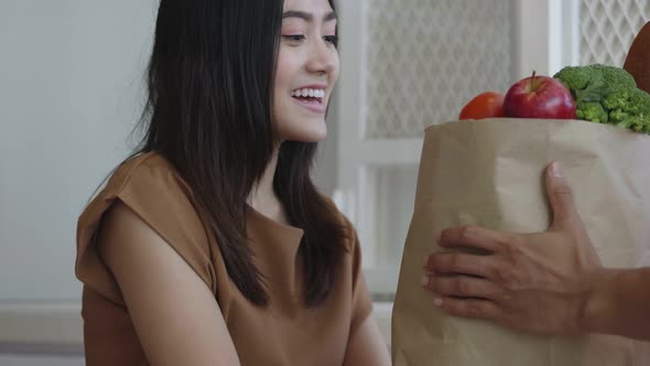 Delivery man giving food to customer woman at home.