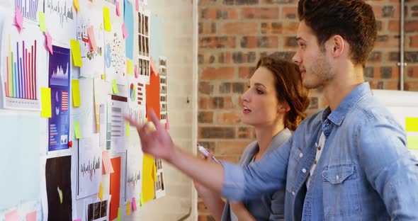 Male and female business executive interacting over whiteboard