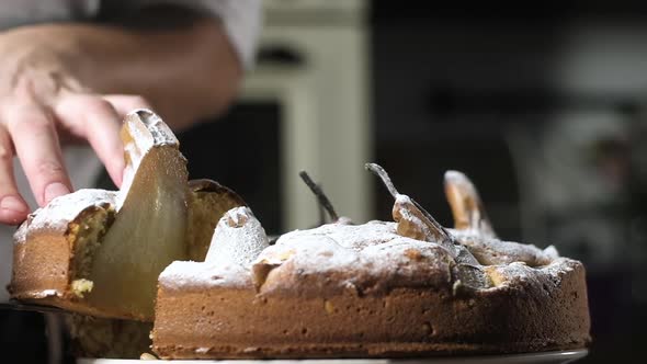 Pear pie. The cook cuts a piece of cake with baked pears. cookies in the kitchen