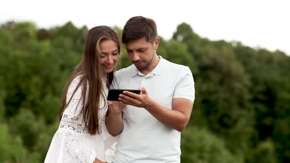 Couple In Love. Man And Woman Looking At Phone In Nature.