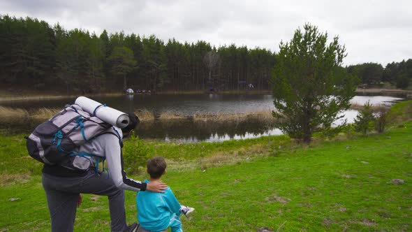 The boy and his father are by the lake.