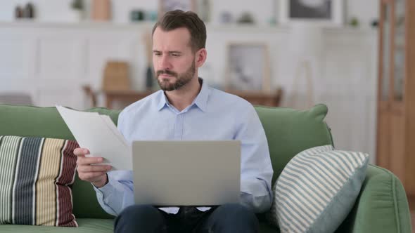 Young Man Working on Documents and Laptop at Home