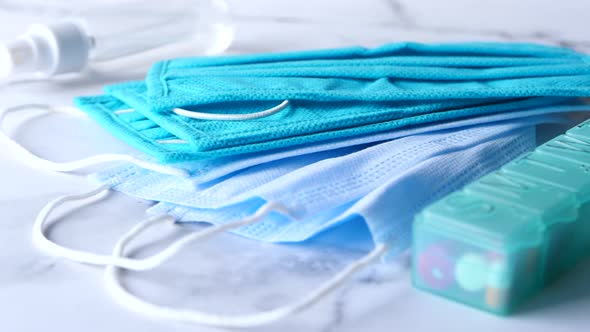 Close Up of Blue Surgical Masks Sanitizer and Pill Box on Table