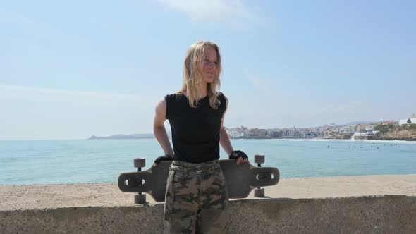 Beautiful and Style Young Girl Posing with a Skateboard at Seafront