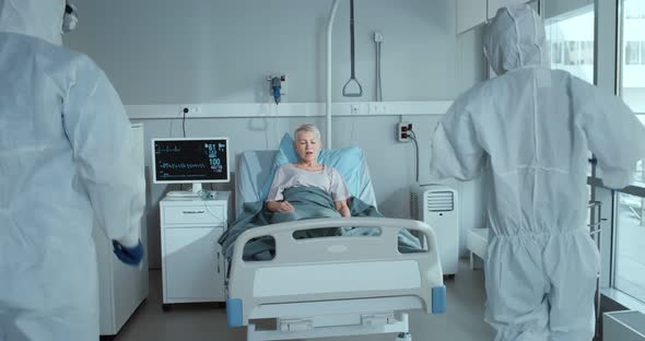 Medical Workers in Ppe Suits Putting Oxygen Mask Ventilator on Female Patient Lying in Hospital Bed