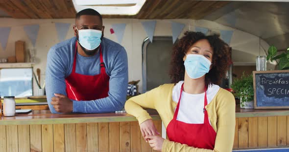 Portrait of african american couple wearing face masks standing near the food truck