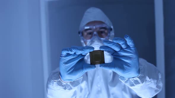 Man in clean room holds up computer cpu microchip