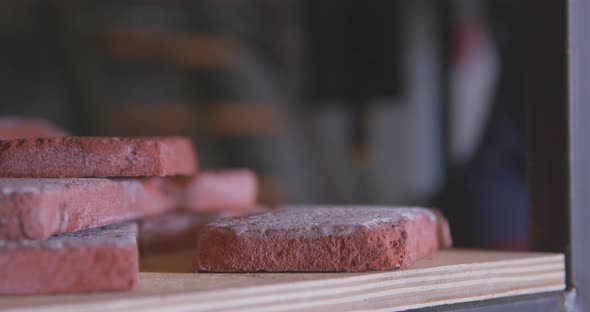 Man in Rubber Gloves Puts Orange Brick Cast on Wooden Shelf