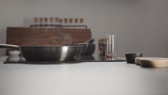 Man Checking Temp of Steel Pan on Electric Hob on Kitchen with Hand