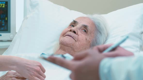 Grey-haired woman laying on therapy bed and answering doctor's questions