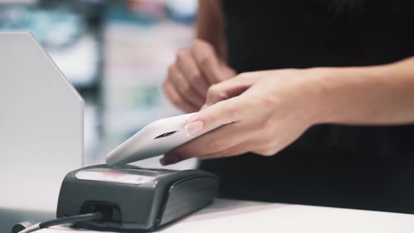 Close Up Side View of Female Hand Brings the NFC Smartphone to Pay