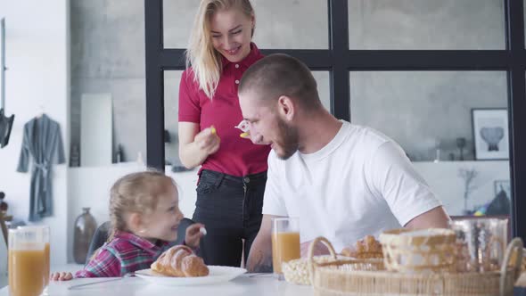 Smiling Young Woman Giving Tasty Nutritional Vitamins To Pretty Daughter and Happy Husband. Portrait