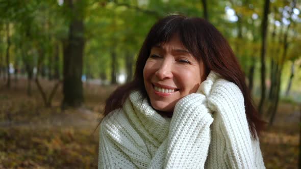 Closeup Portrait of Happy Mature Woman with Toothy Smile Looking at Camera Caressing Face