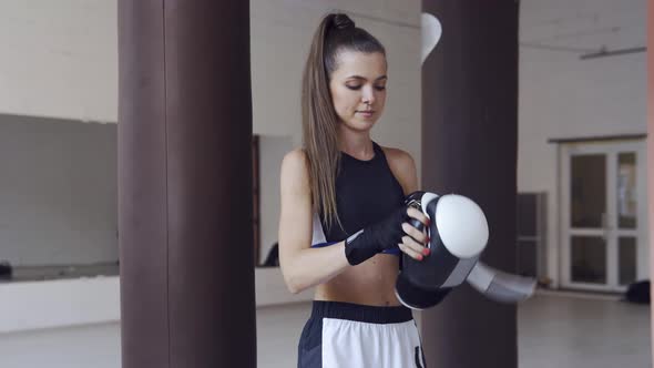 A Young Athlete Wearing Boxing Gloves To Prepare for Boxing Training with Punching Bags in the Gym