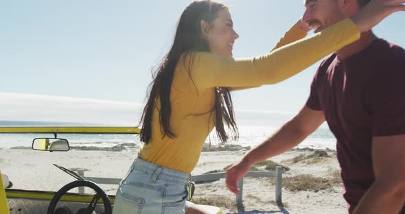 Happy caucasian couple hugging near beach buggy by the sea