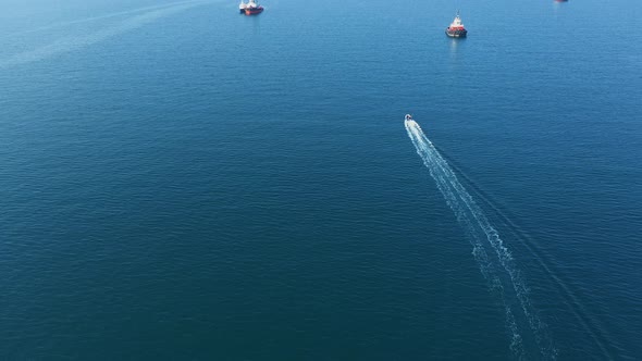 Aerial View of Small Boat Sails on Blue Sea Among Larger Vessels