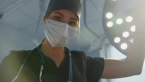 A Female Doctor Adjusts a Surgical Lamp Before Surgery in a Hospital