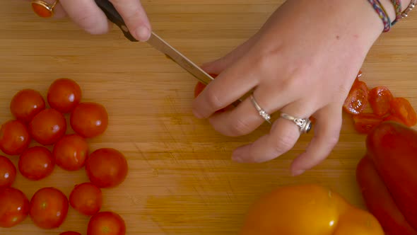 woman's hands cutting cherry tomatoes - cooking pasta