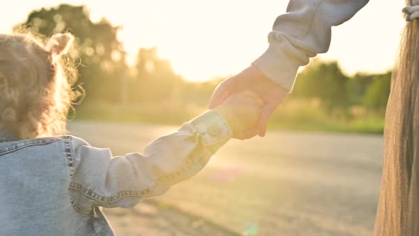 Slow motion of mom walking with her daughter holding hands