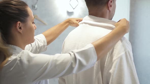 Woman Takes Off White Coat From Adult Man