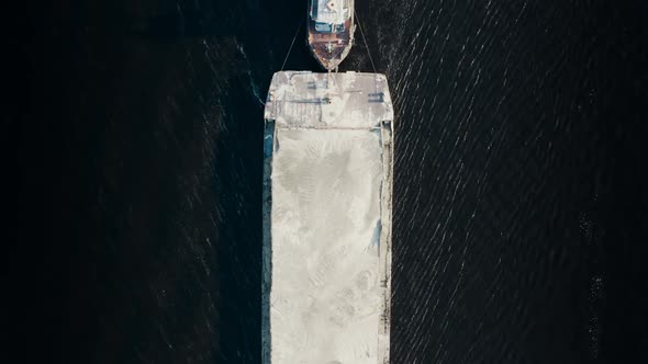 Top Aerial View of Tugboat Towing Large Barge to Industrial Port